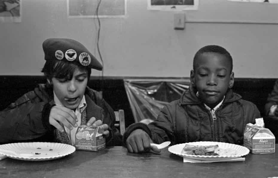 Two young boys eat during a free breakfast for children program sponsored by the Black Panther Party in 1969.